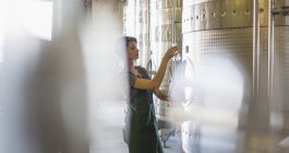 Winzer testet Wein aus Edelstahlbottich im Weinkeller — Stockfoto