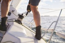 Man sailing turning cable winch on heeling sailboat — Stock Photo