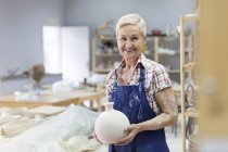Retrato sorrindo sênior mulher segurando vaso de cerâmica no estúdio — Fotografia de Stock