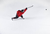 Eishockeyspieler in roter Uniform schießt Puck aufs Eis — Stockfoto