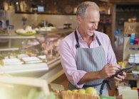 Smiling grocery worker checking inventory with digital tablet and stylus in market — Stock Photo