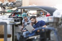 Mechanics working with clipboard and laptop in auto repair shop — Stock Photo