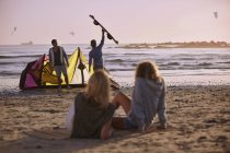 Жінки спостерігають, як чоловіки готуються до кемпінгу на пляжі — стокове фото
