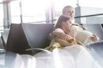 Schwangere Mutter und schlafende Tochter warten im Abflugbereich des Flughafens — Stockfoto