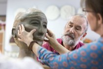 Mulher esculpindo cara de barro no estúdio de cerâmica — Fotografia de Stock