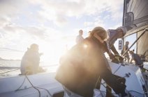 Друзья регулируют парусное оборудование на солнечной парусной лодке — стоковое фото