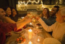 Friends toasting champagne glasses at candlelight table — Stock Photo
