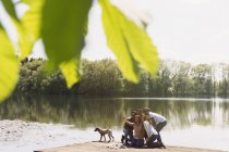 Друзі з телефоном знімають селфі на сонячному березі озера док — стокове фото