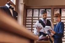 Рабочий показывает бизнесмену рубашки в магазине мужской одежды — стоковое фото
