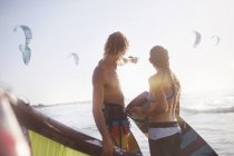 Couple watching kiteboarders over sunny ocean — Stock Photo
