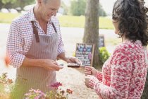 Woman watching plant nursery worker using credit card reader — Stock Photo