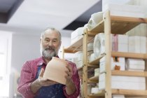 Uomo anziano esaminando vasellame in studio — Foto stock