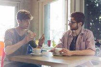 Чоловіки розмовляють і п'ють каву в кафе — стокове фото