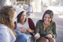 Teenage girls with cell phone laughing and hanging out — Stock Photo