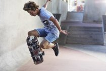 Adolescente menino lançando skate no parque de skate — Fotografia de Stock