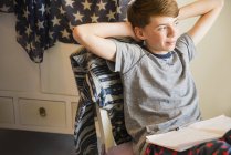 Selbstbewusster Junge macht Hausaufgaben mit den Händen hinter dem Kopf — Stockfoto