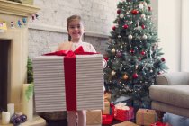 Portrait enthusiastic girl holding large Christmas gift — Stock Photo