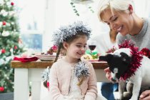 Mother and daughter feeding dog at Christmas dinner — Stock Photo
