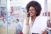 Lächelnde Geschäftsfrau mit Papierkram am Telefon — Stockfoto