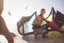 Uomo che prepara aquilone kiteboarding sulla spiaggia soleggiata — Foto stock