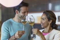 Sonriente pareja tostando copas de vino blanco - foto de stock