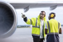 Bodenpersonal der Flugsicherung spricht in der Nähe des Flugzeugs auf dem Rollfeld des Flughafens — Stockfoto