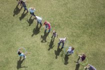 People spinning in plastic hoops in sunny field — Stock Photo