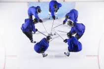 Hockey players in blue uniforms huddling around puck on ice — Stock Photo