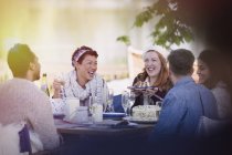 Freunde lachen beim Kuchen essen und Champagner trinken am Terrassentisch — Stockfoto