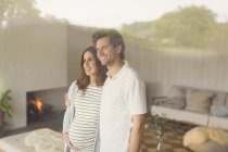 Smiling pregnant couple looking out living room window — Stock Photo