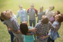 Team forming connected circle basking in sunny field — Stock Photo