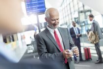 Businessman texting with cell phone in airport concourse — Stock Photo
