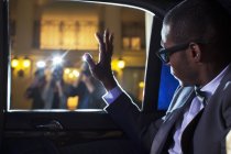 Celebrity in limousine waving at paparazzi photographers — Stock Photo