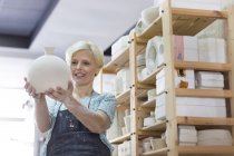 Mujer sonriente sosteniendo jarrón de cerámica en el estudio - foto de stock