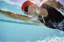 Nadador masculino nadando subaquático na piscina — Fotografia de Stock