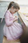 Girl in fairy wings coloring at dining table — Stock Photo