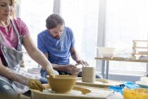 Mature couple using pottery wheels in studio — Stock Photo