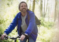 Hombre sonriente ciclismo de montaña en los bosques - foto de stock