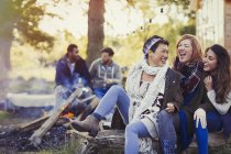 Female friends laughing and roasting marshmallows at campfire — Stock Photo