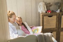 Schwangere Mutter und Tochter lesen im Kinderzimmer Märchen — Stockfoto