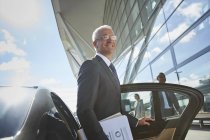 Smiling businessman arriving at airport getting out of town car — Stock Photo