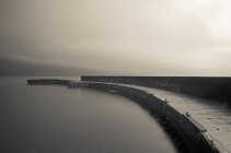 Monochrome image of old pier over water — Stock Photo