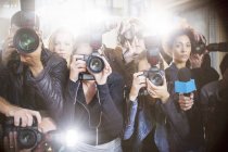 Portrait of serious paparazzi photographers pointing cameras — Stock Photo