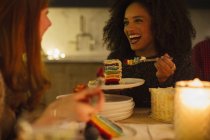 Сміються друзі насолоджуються тортами за свічковим столом — стокове фото