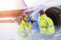 Airport ground crew workers talking near airplane — Stock Photo