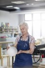 Улыбающаяся пожилая женщина держит вазу для керамики в студии — стоковое фото