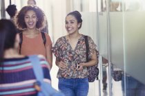 Estudantes universitárias sorridentes caminhando no corredor — Fotografia de Stock