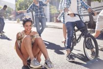 Entusiasta ragazza adolescente skateboard con gli amici sulla strada urbana soleggiata — Foto stock
