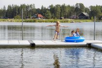 Rapaz a saltar da doca para o lago — Fotografia de Stock