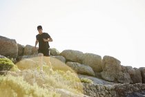 Триатлонист бегает по солнечной скалистой тропе — стоковое фото